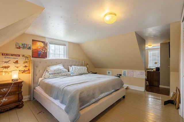 bedroom with lofted ceiling, light wood finished floors, and baseboards