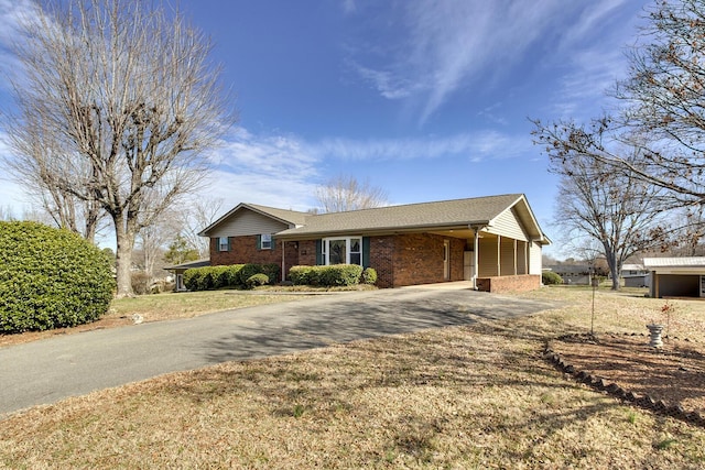 ranch-style home with driveway, an attached carport, and brick siding