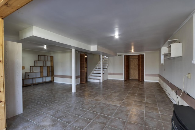 finished below grade area with dark tile patterned flooring, baseboards, and stairs