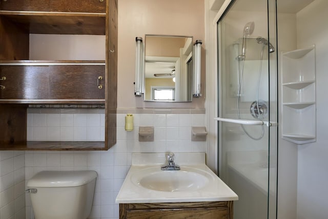 full bathroom with toilet, vanity, a shower with shower door, and tile walls