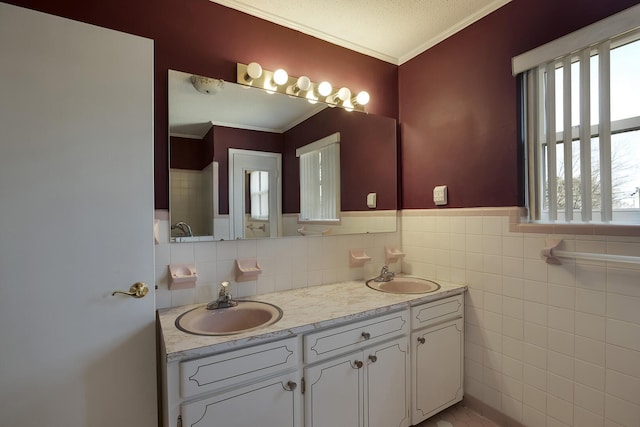 full bathroom with crown molding, a sink, tile walls, and double vanity