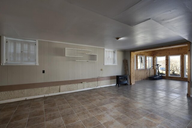 empty room with a wood stove, tile patterned flooring, and baseboards