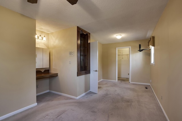 corridor featuring baseboards, a textured ceiling, and carpet flooring