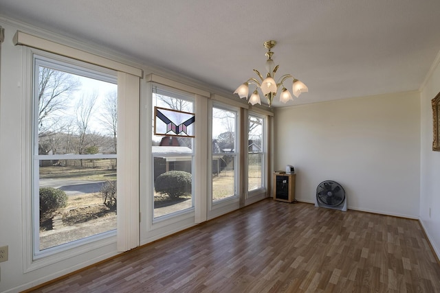 unfurnished dining area featuring baseboards, wood finished floors, and a notable chandelier