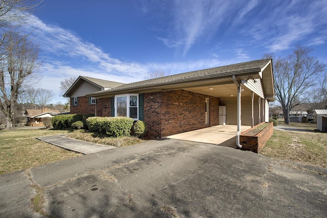 view of side of property featuring concrete driveway, an attached carport, and brick siding