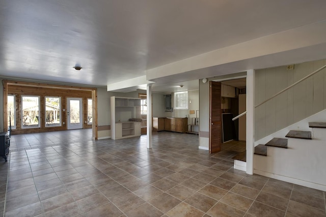 unfurnished living room featuring tile patterned flooring, baseboards, and stairs