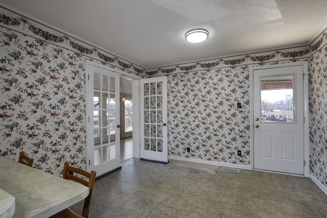 dining area featuring a textured ceiling, french doors, visible vents, and wallpapered walls