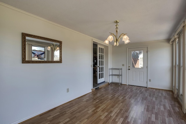 entryway featuring baseboards, crown molding, wood finished floors, and a notable chandelier