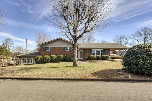 view of front of property with a front yard, an attached carport, and brick siding