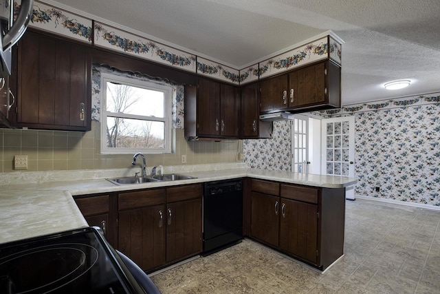 kitchen featuring light countertops, a sink, a textured ceiling, black appliances, and wallpapered walls