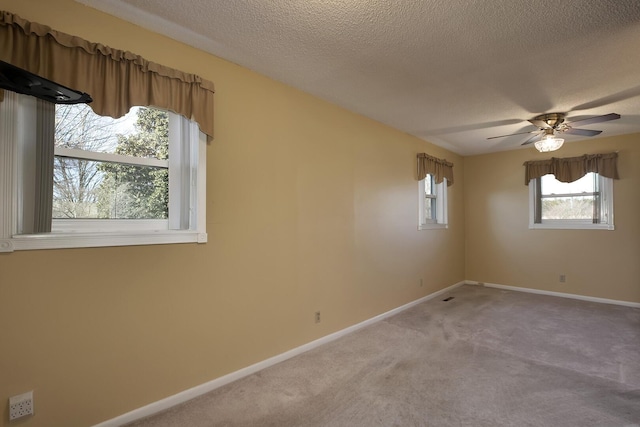 spare room featuring light carpet, ceiling fan, a textured ceiling, and baseboards