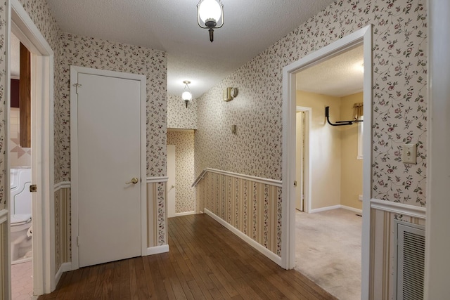 corridor with wallpapered walls, visible vents, and a textured ceiling