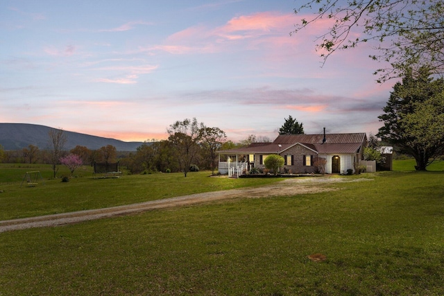 view of front facade with a yard, dirt driveway, covered porch, and a mountain view