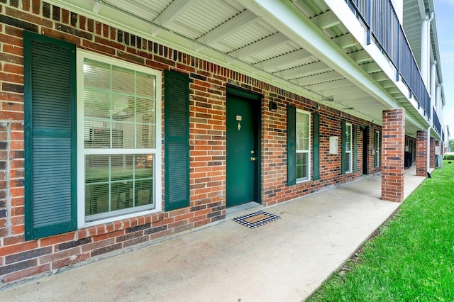 view of exterior entry featuring brick siding and covered porch