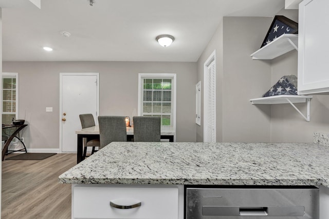 kitchen with open shelves, light wood-style flooring, light stone counters, baseboards, and white cabinets