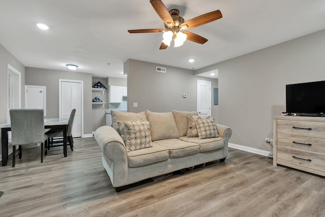 living area featuring ceiling fan, baseboards, light wood-style floors, and recessed lighting