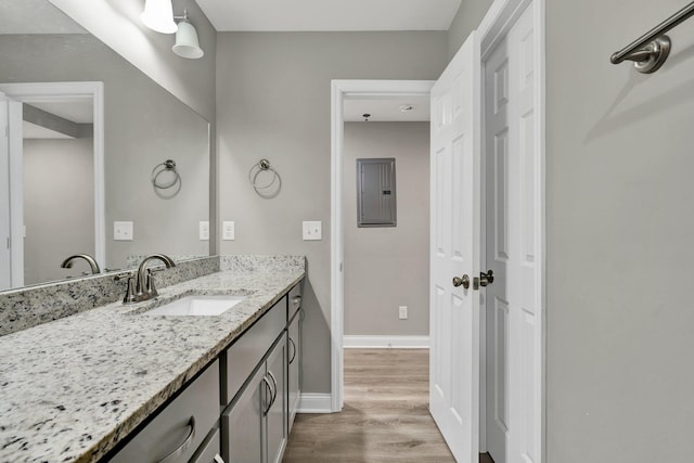 bathroom with electric panel, baseboards, wood finished floors, and vanity