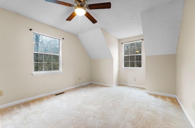 bonus room featuring ceiling fan, lofted ceiling, light colored carpet, and a textured ceiling