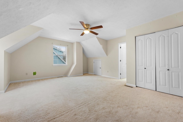 bonus room featuring ceiling fan, light colored carpet, vaulted ceiling, and a textured ceiling