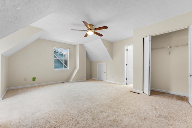 additional living space featuring lofted ceiling, ceiling fan, light colored carpet, and a textured ceiling