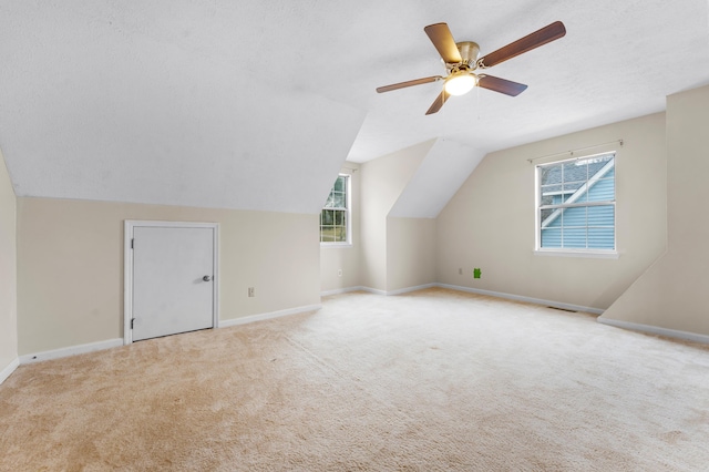 bonus room with light carpet, ceiling fan, vaulted ceiling, and a textured ceiling