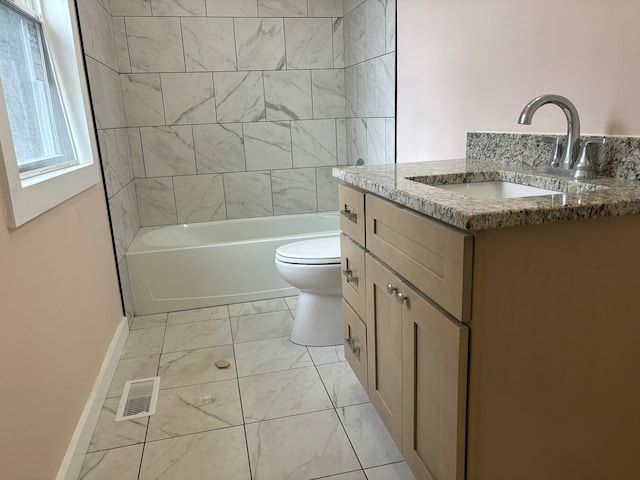 full bathroom featuring tiled shower / bath, vanity, and toilet