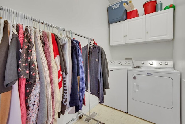 clothes washing area featuring washing machine and dryer and cabinet space