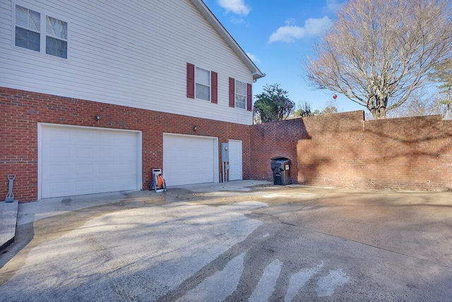 view of property exterior featuring driveway, brick siding, and an attached garage