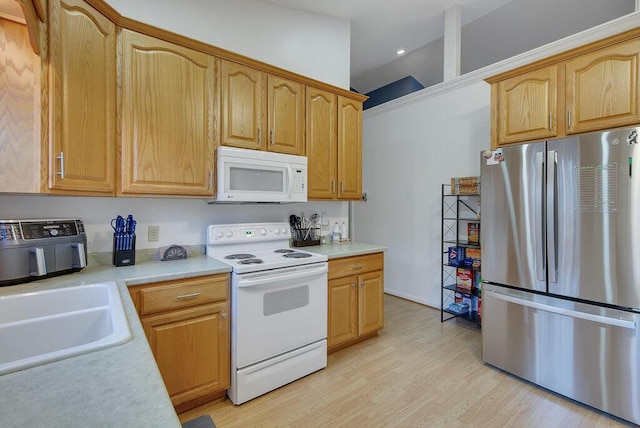 kitchen with recessed lighting, light countertops, light wood-style flooring, a sink, and white appliances