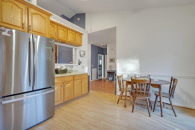 kitchen with vaulted ceiling, light countertops, light wood-type flooring, and freestanding refrigerator