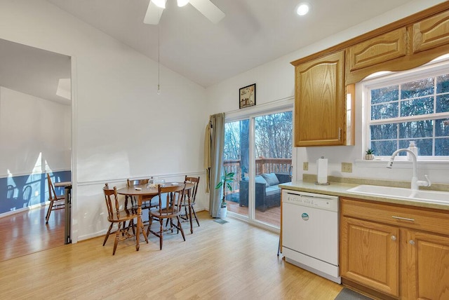 kitchen featuring lofted ceiling, a sink, light wood-style floors, light countertops, and dishwasher