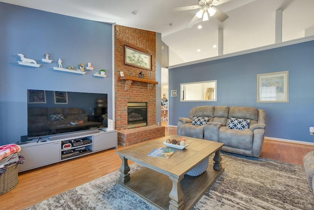 living room with ceiling fan, a fireplace, wood finished floors, and baseboards