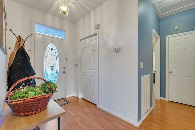 foyer entrance with light wood finished floors, visible vents, and baseboards