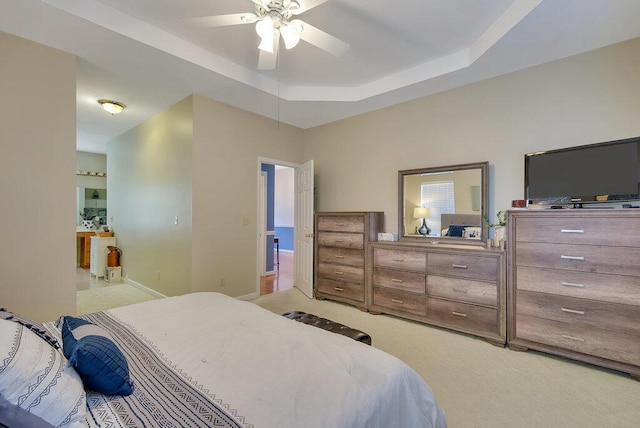 bedroom featuring a tray ceiling, light colored carpet, ceiling fan, and baseboards