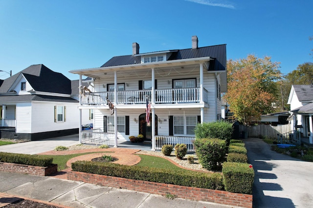 view of front of house featuring a balcony, a chimney, metal roof, a standing seam roof, and a porch