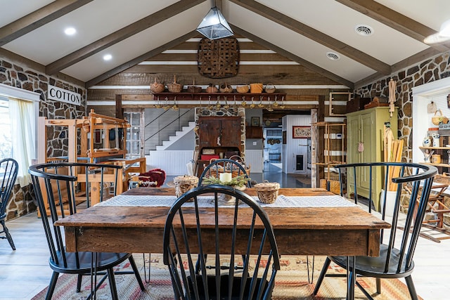 dining room with lofted ceiling with beams and hardwood / wood-style flooring