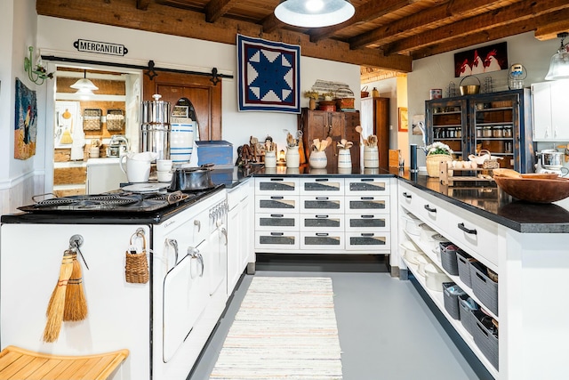 kitchen featuring kitchen peninsula, pendant lighting, a barn door, and white cabinets