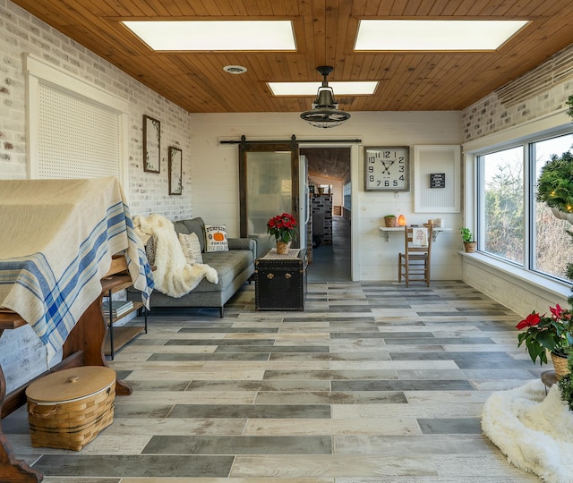 sunroom featuring wooden ceiling, a skylight, and a barn door