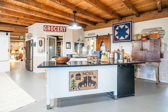 kitchen featuring concrete floors, hanging light fixtures, kitchen peninsula, and a barn door