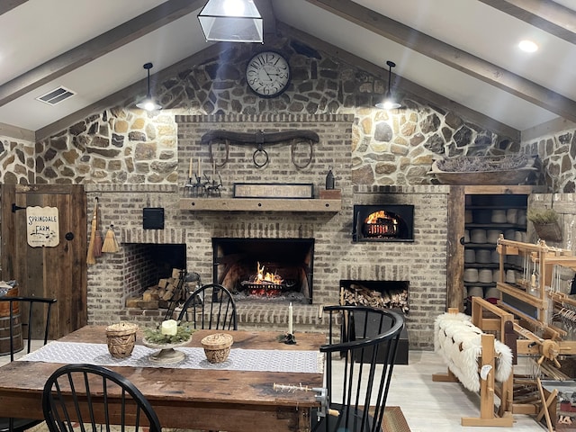 dining room with light wood-type flooring, lofted ceiling with beams, and a fireplace