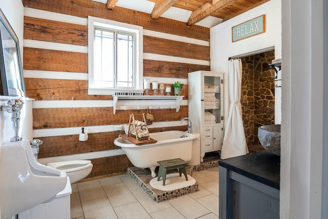 bathroom with tile patterned floors, toilet, beam ceiling, and a bathing tub