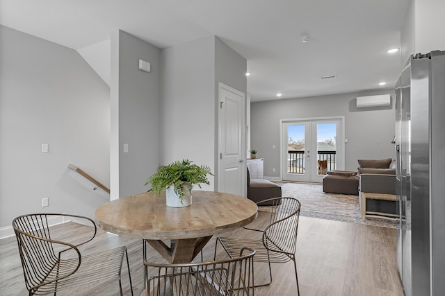 dining area featuring french doors, a wall unit AC, and light hardwood / wood-style flooring