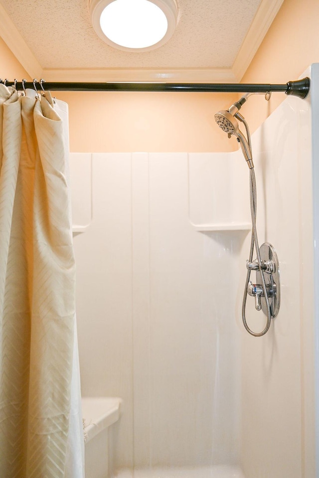 bathroom featuring a shower with shower curtain, a textured ceiling, and ornamental molding