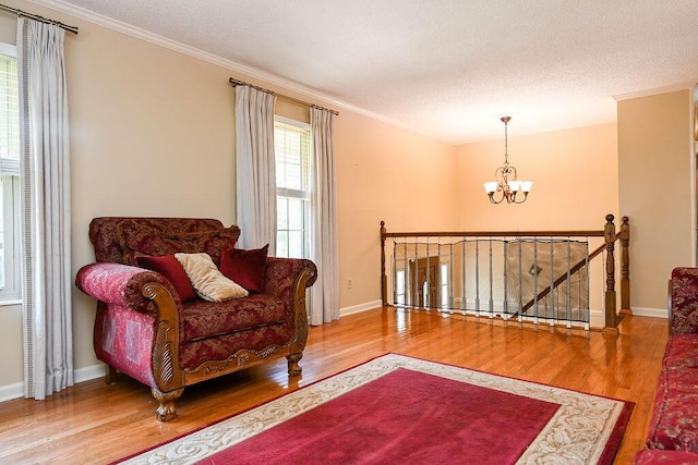 living area featuring a textured ceiling, hardwood / wood-style flooring, an inviting chandelier, and crown molding