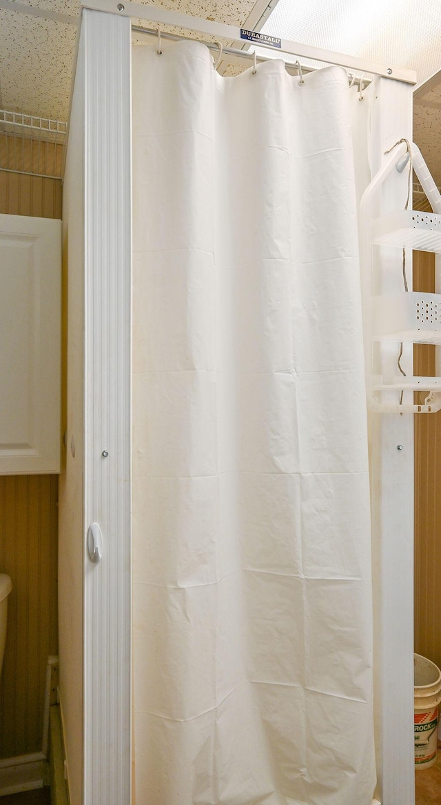 bathroom featuring a shower with curtain and wooden walls