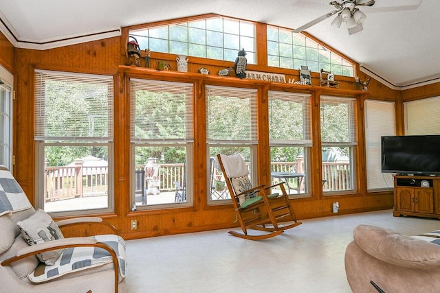 interior space with ceiling fan, lofted ceiling, and wood walls