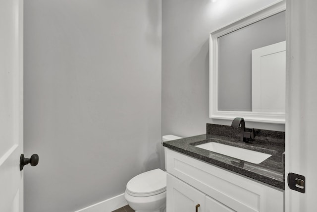 kitchen featuring baseboards, dark wood-style flooring, dark stone countertops, and white cabinets