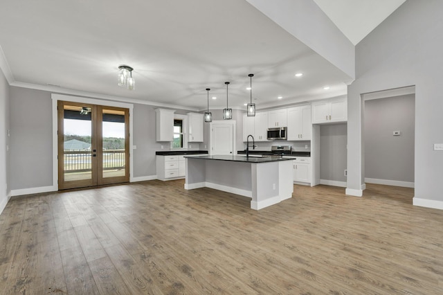 unfurnished living room with ornamental molding, a raised ceiling, baseboards, and wood finished floors