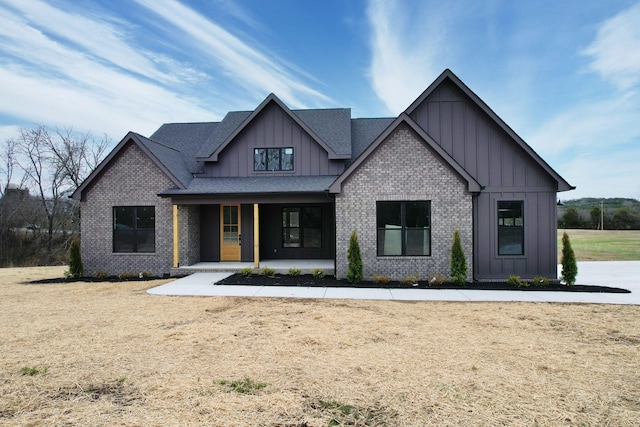 modern farmhouse style home with covered porch, board and batten siding, a front yard, a standing seam roof, and metal roof