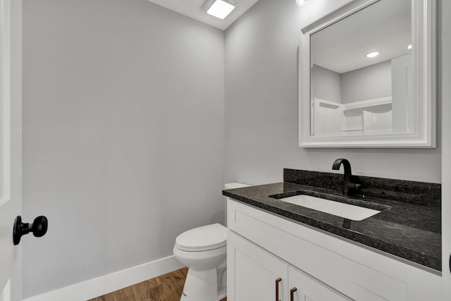 bathroom with vanity, wood finished floors, toilet, and baseboards